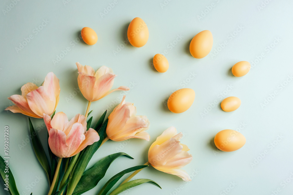 Yellow Easter eggs and tulip flowers on green background. Easter concept. Top view, flat lay