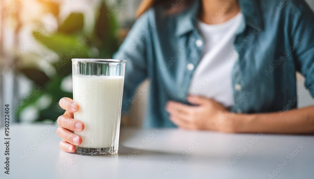Blurred woman's hand on table with milk, depicting lactose intolerance Blurred woman's hand on table with milk, depicting lactose intolerance
