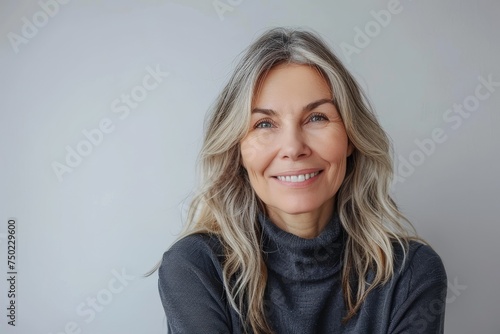 Beautiful middle aged woman smiling for a portrait and a happy older lady with gray hair posing in a studio