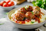 Beef meatballs in tomato sauce served with mashed potatoes on a white table