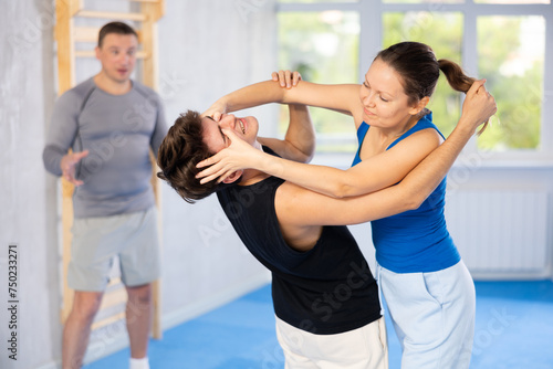 Young guy and woman train to perform effective blows and impact on pain points eyes groin while learning self-defense techniques. Lesson in presence of experienced instructor
