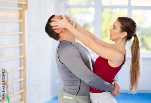 Young woman and man practicing self defense techniques in gym