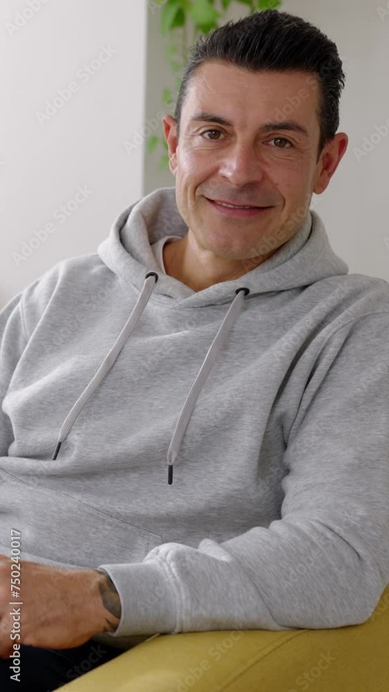 Vertical portrait of mid adult handsome man looking at camera. Front view portrait of confident male relaxed on sofa at home. 40s people concept. Vertical portrait of mid adult handsome man looking at camera. Front view portrait of confident male relaxed on sofa at home. 40s people concept.