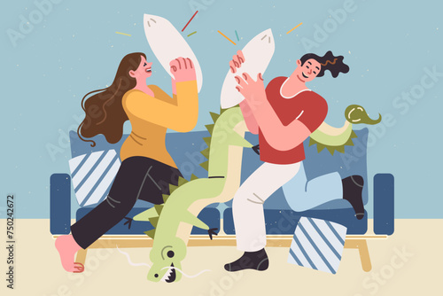 Carefree couple fights with pillows, sitting on sofa, enjoying pleasure of relaxing together