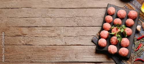 Board with raw meatballs made of fresh forcemeat on wooden background with space for text photo