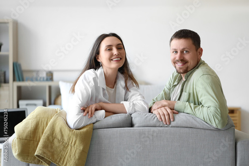 Happy young couple sitting on sofa at home