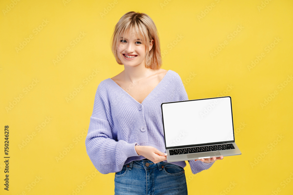 Smiling beautiful young woman with braces, holding laptop, showing mockup, looking at camera Smiling beautiful young woman with braces, holding laptop, showing mockup, looking at camera