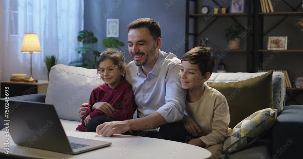 Smiling father and children using laptop talking during online video conference call chat with relatives or friends, sitting on couch in the evening. Happy family together. Distance connection concept Smiling father and children using laptop talking during online video conference call chat with relatives or friends, sitting on couch in the evening. Happy family together. Distance connection concept