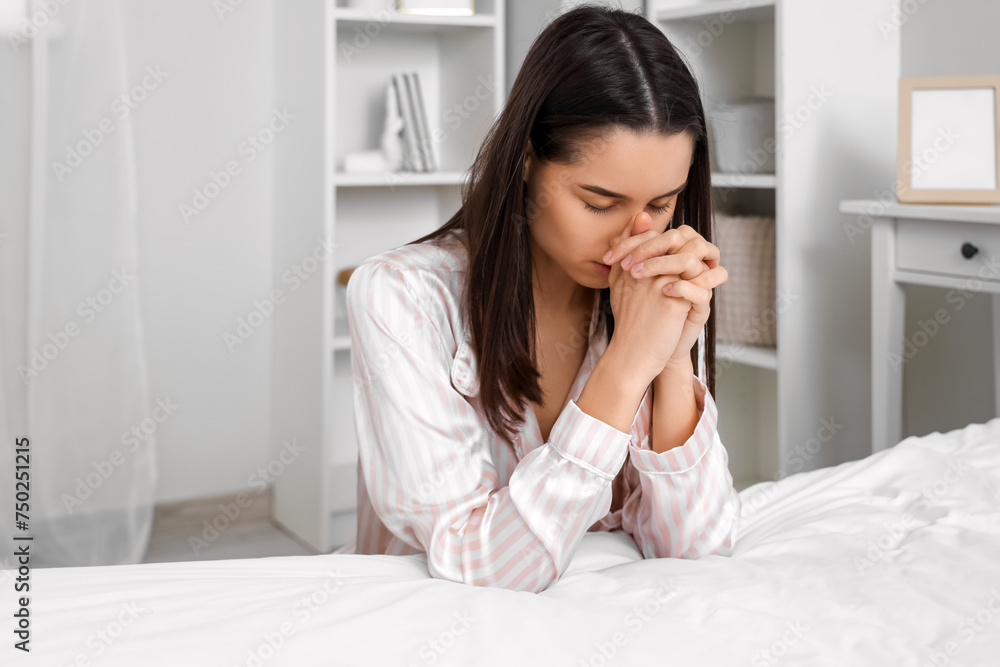 Beautiful young woman praying in bedroom at home Beautiful young woman praying in bedroom at home