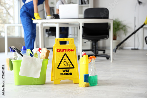 Cleaning supplies with caution sign in office, closeup