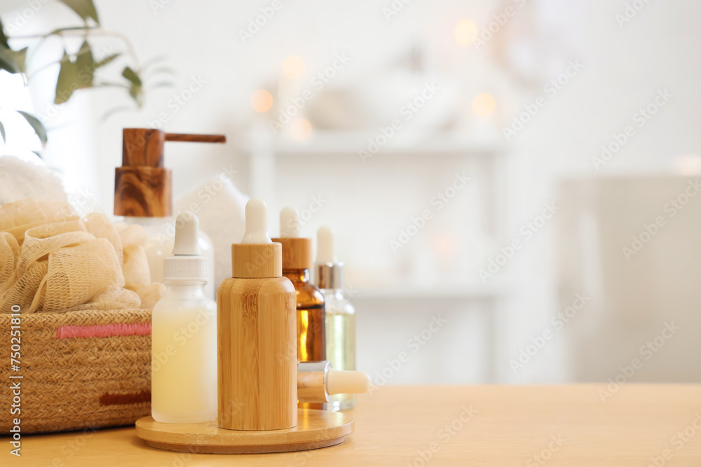 Cosmetic dropper bottles with loofah on table in bathroom, closeup Cosmetic dropper bottles with loofah on table in bathroom, closeup
