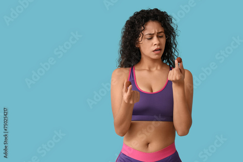 Thoughtful young African-American woman with sweet chocolate candies on blue background © Pixel-Shot