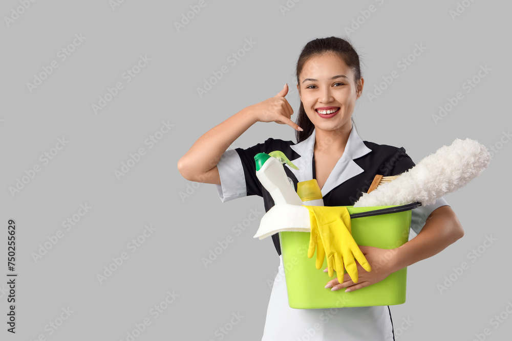 Young Asian chambermaid with cleaning supplies showing Young Asian chambermaid with cleaning supplies showing