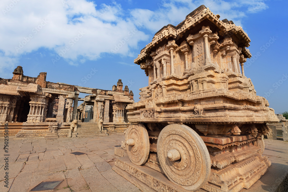 Ancient stone chariot with intricate carvings and medieval ruins at Vijaya Vittala temple at Hampi, Karnataka, India.