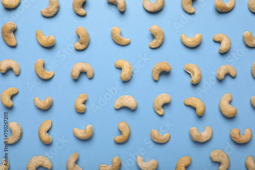 Many tasty cashew nuts on light blue background, top view