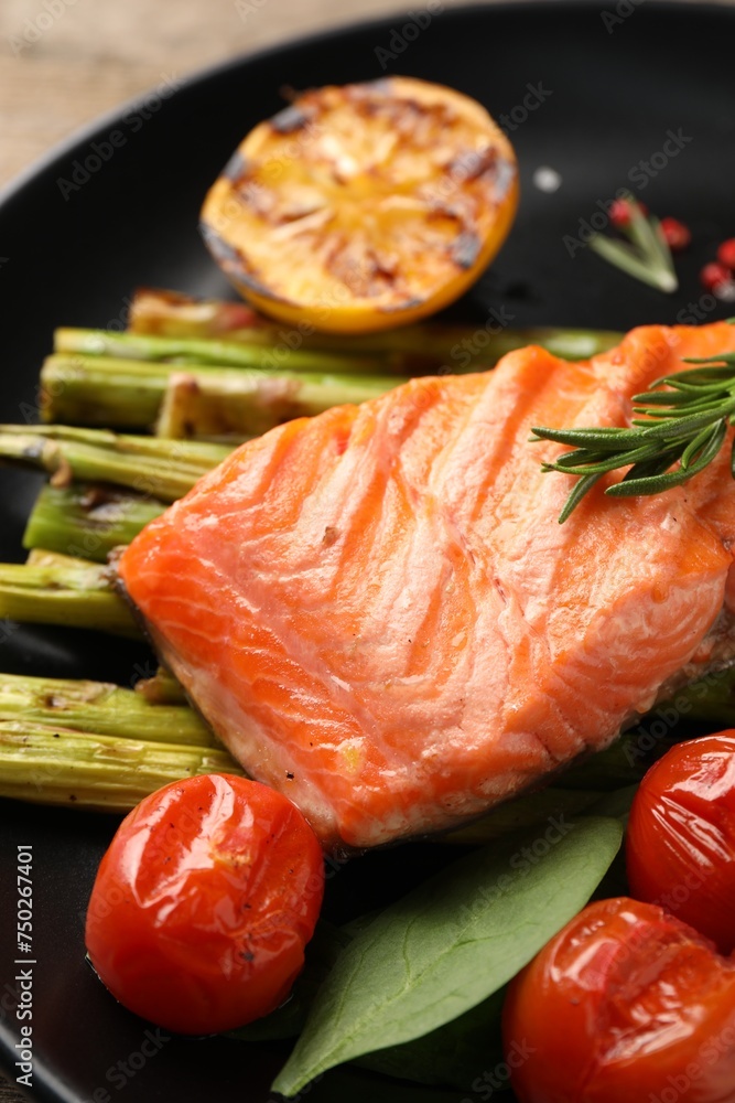 Tasty grilled salmon with tomatoes, asparagus and rosemary on plate, closeup Tasty grilled salmon with tomatoes, asparagus and rosemary on plate, closeup