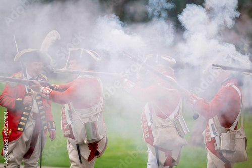 Obraz na plátně Reenactors portraying British soldiers fire their weapons during the revolution