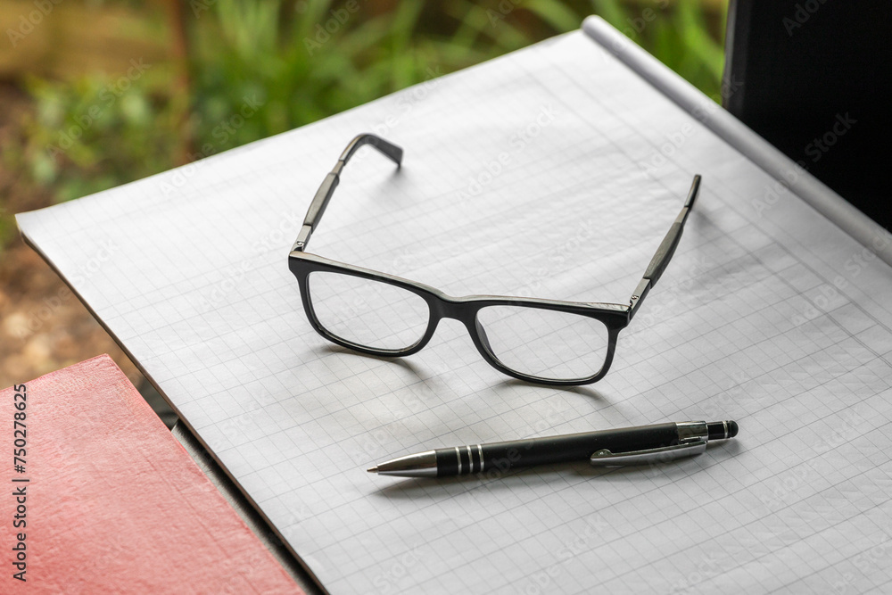 Black Pen and Glasses Resting on Blank Notebook Paper Black Pen and Glasses Resting on Blank Notebook Paper