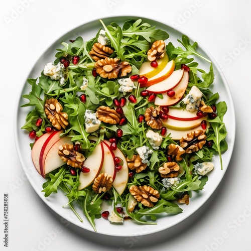 Salad with autumnal elements: wild arugula, pomegranate seeds, pear slices, Ewe's blue cheese, walnuts, drizzled with balsamic dressing, served on a white round plate against a white background in a t photo