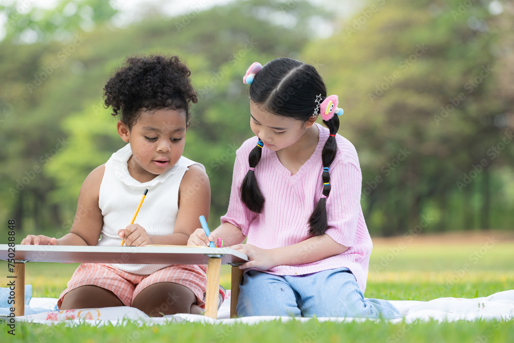 Happy family enjoying a picnic in the park, Children are having fun drawing on paper placed on the table. Happy family enjoying a picnic in the park, Children are having fun drawing on paper placed on the table.