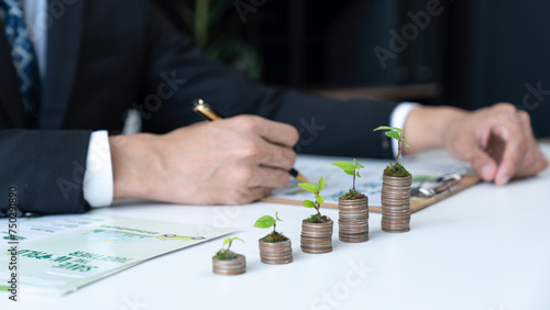 Businessman with coin stack at his office as sustainable money growth investment or eco-subsidize. Green corporate promot and invest in environmental awareness. Gyre