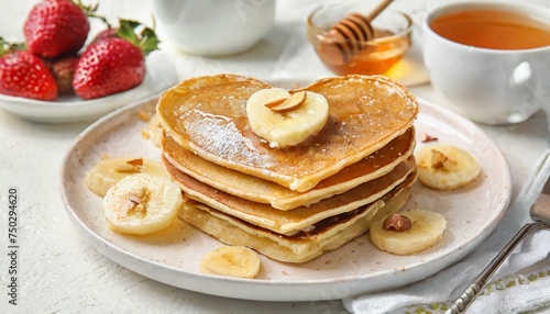 Plate with tasty pancakes in shape of heart  dried banana and honey on light background.