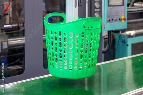 Automated process of molding plastic products on a CNC machine. The robotic arm of the machine moves the newly made green plastic basket. Injection molding of plastic objects