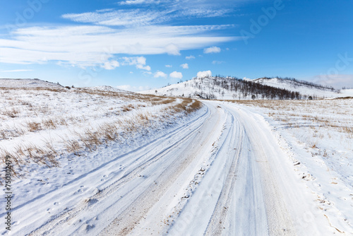 Snowy dirt road on Teheran steppe to Baikal Lake coast on sunny cold February day. Beautiful winter landscape. Natural background. Winter travels and outdoor recreation © Katvic