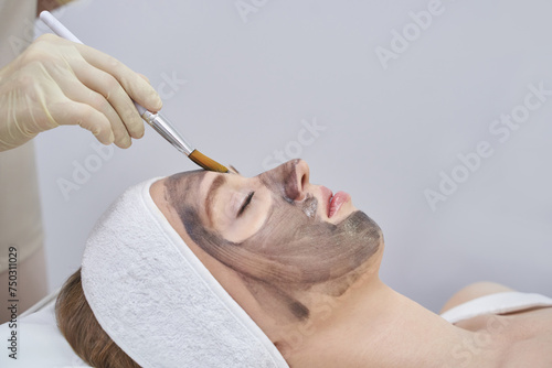 A beauty spa offers a laser facial treatment. A woman undergoes a rejuvenating peel with a carbon mask, promoting skincare and reducing pigmented lesions