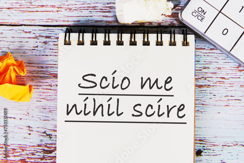 Scio me nihil scire It is translated from Latin as I know I don't know anything. It is written on the notebook in close-up photo