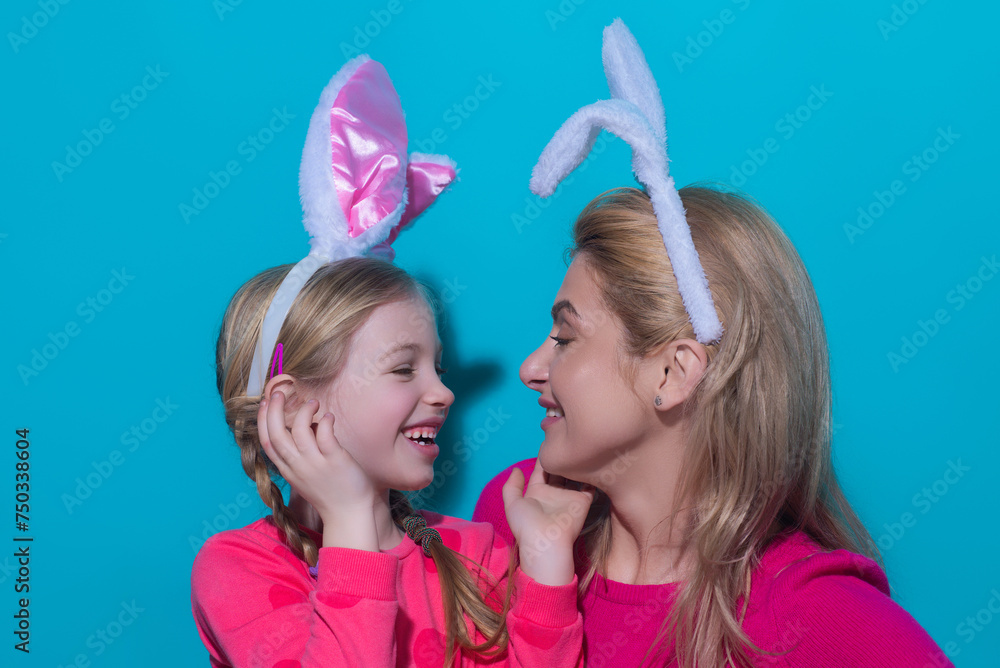 A mother and her daughter painting Easter eggs. Happy family preparing for Easter. Mother and daughter painting eggs. Mom and child wearing easters bunny ears isolated in blue studio. A mother and her daughter painting Easter eggs. Happy family preparing for Easter. Mother and daughter painting eggs. Mom and child wearing easters bunny ears isolated in blue studio.