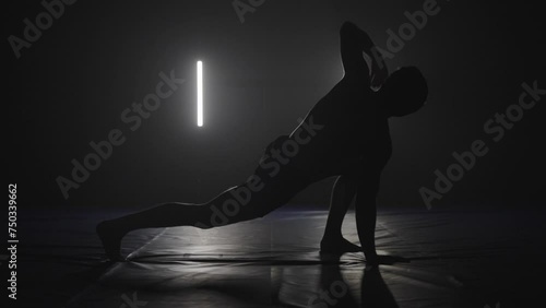male athlete doing yoga stretches as workout warming up in black and white studio, silhouette yoga photo