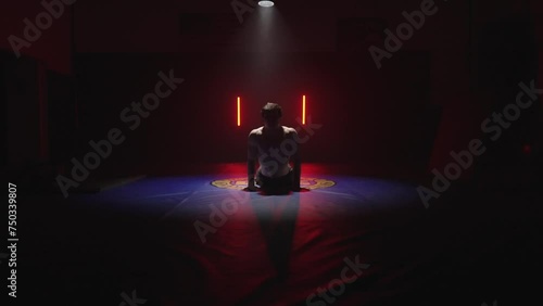 kickbox fighter stretching before MMA workout, male athlete, dark gym studio photo