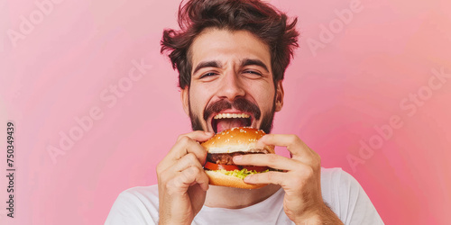 portrait of a young man eating delicious hamburger on color background  copy space