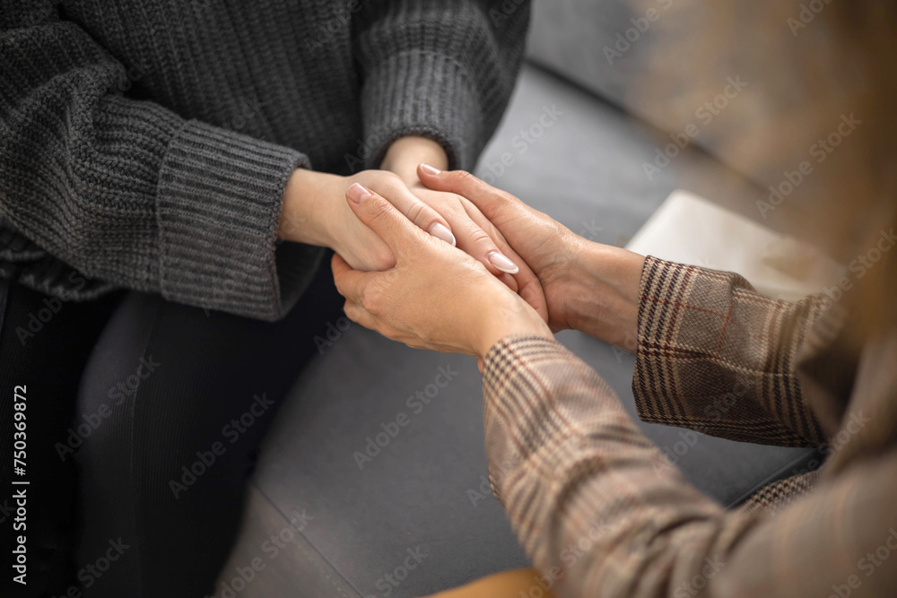 Two woman holding hands to each other concept of support care trust help sisterhood top view closeup