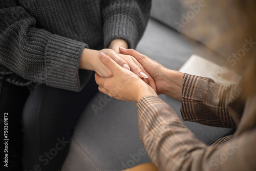 Two woman holding hands to each other concept of support care trust help sisterhood top view closeup photo