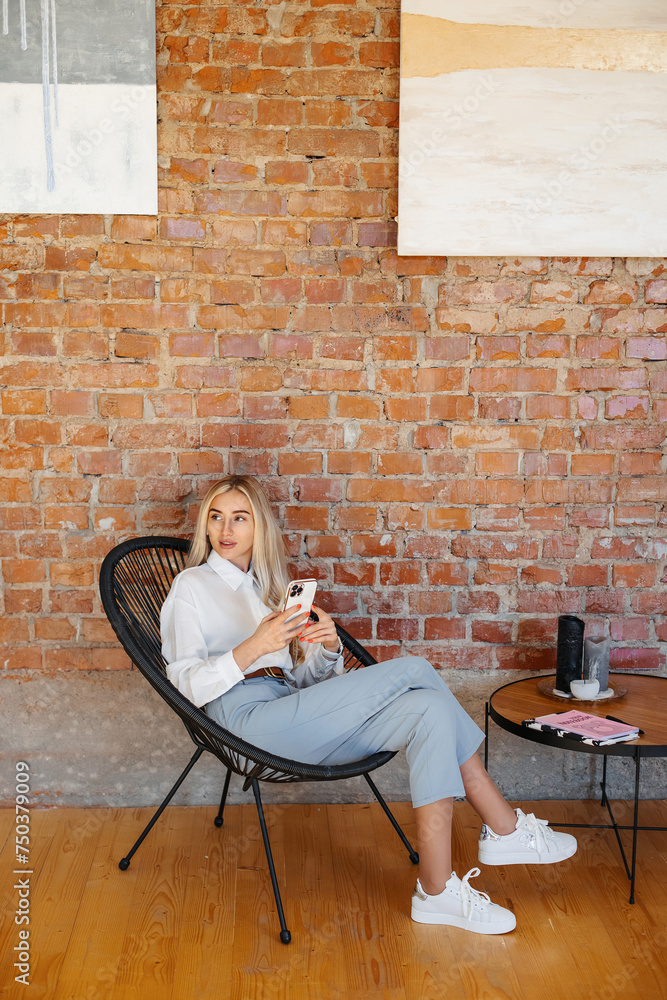 Stylish woman sitting in the office with a brick wall Stylish woman sitting in the office with a brick wall