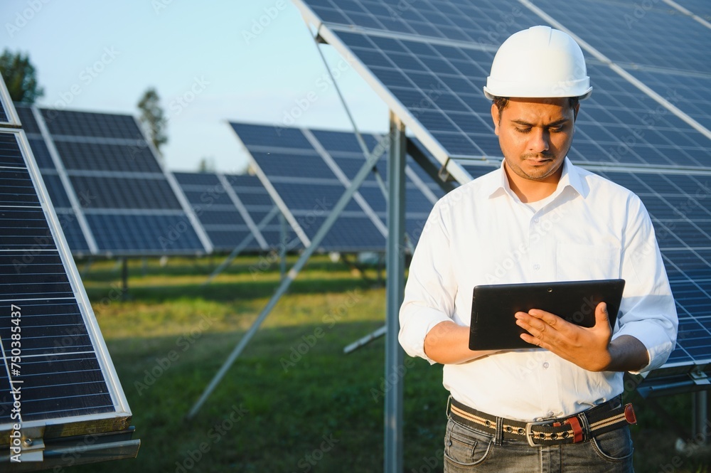 Portrait of Young indian male engineer standing near solar panels, with clear blue sky background, Renewable and clean energy. skill india, copy space