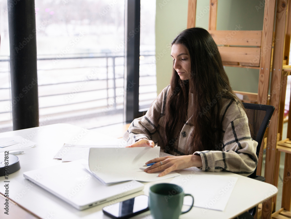 Diligent Office Worker Reviewing Documents at Modern Workplace During Business Hours Diligent Office Worker Reviewing Documents at Modern Workplace During Business Hours