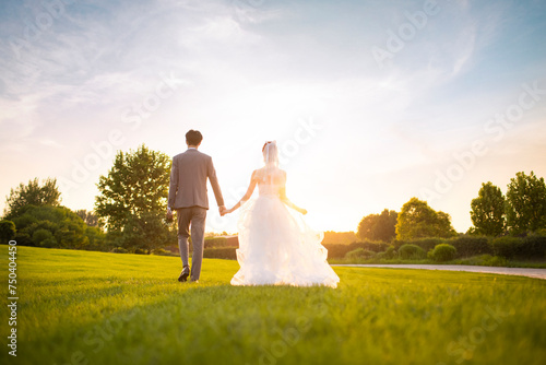 Happy bride and groom walking on the grass photo
