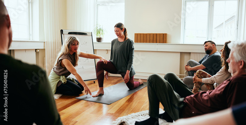 Yoga instructor teaching the crescent lunge pose for her class in a yoga studio photo