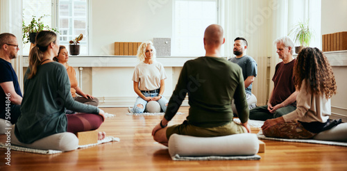 Yoga instructor teaching students meditation while they sit in n circles on a floor photo