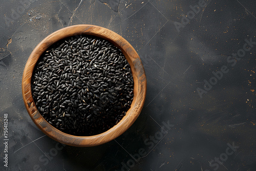 grains de riz noir dans un bol en bois d'olivier, sur un fond texturé noir avec espace négatif pour texte, copyspace