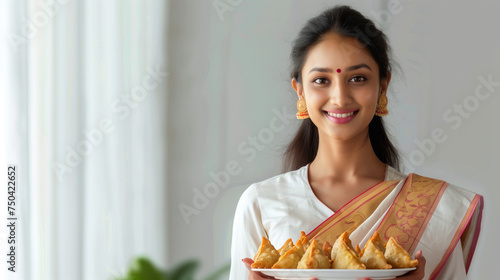 Young indian lady in saree holding a plate with delectable samosas