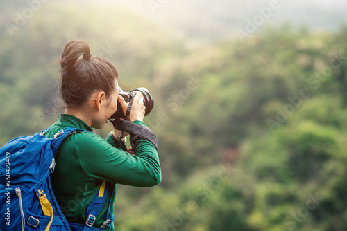 Woman photographer taking photo on spring mountain top #750429469