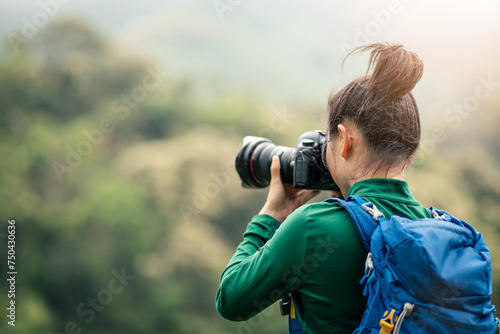 Woman photographer taking photo on spring mountain top