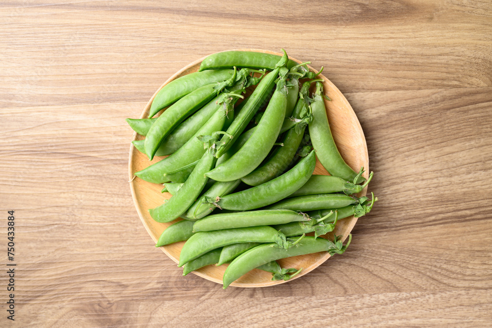 Fresh green pea in wooden plate on wooden background, Table top view Fresh green pea in wooden plate on wooden background, Table top view
