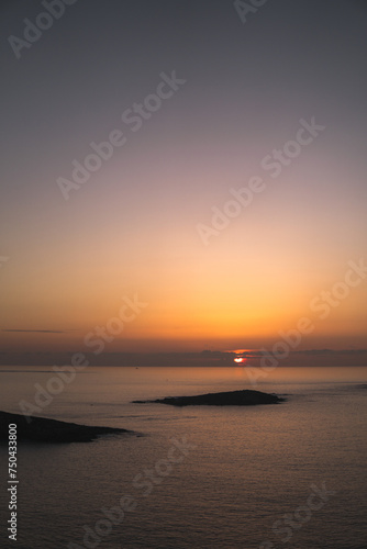 Spectacular sunset view from Monteferro's Rosa de los Vientos. Tranquil sea, clean horizon, Estelas islands' silhouettes, orange sky, and sun setting amid low grey clouds. photo