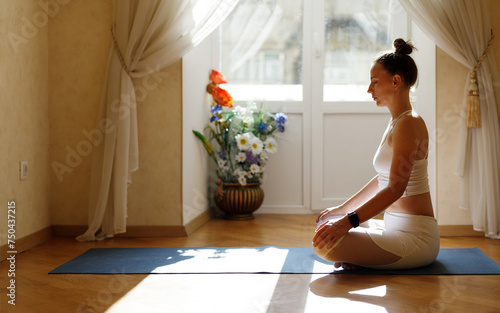 Fitness woman in white sportswear meditating on the mat in the morning.