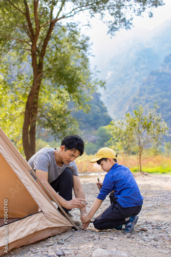 Little boy setting up camping tent together with his father photo